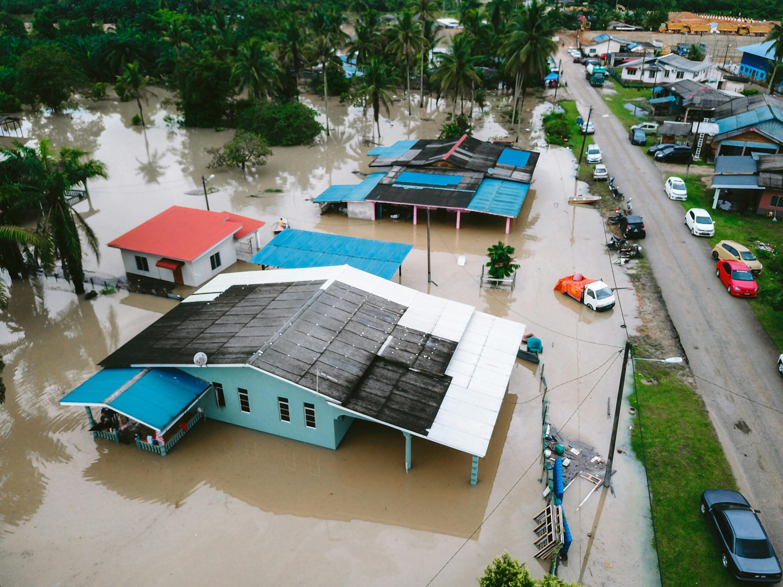 Services Aerial view of a flooded village in Kijal, Terengganu, Malaysia, showcasing submerged houses and streets.